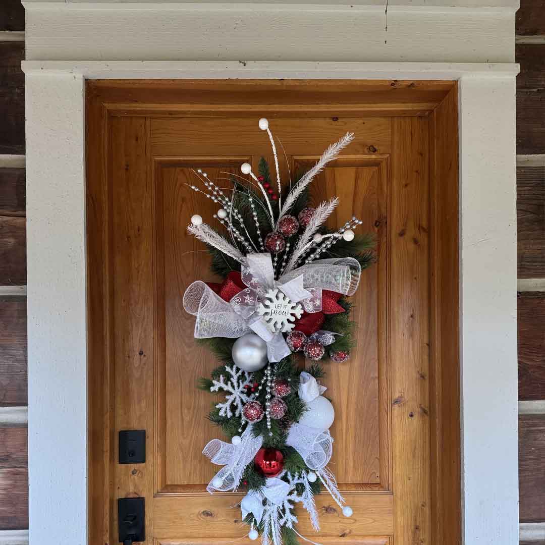 Holiday swag with evergreen, ribbon, and a ‘Let It Snow’ sign hanging on a wooden door at Broadwater Hot Springs in Helena, Montana.